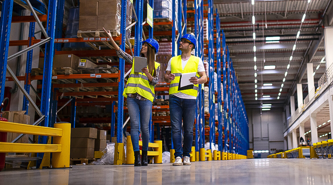 Shot of two workers walking through large warehouse center, obse